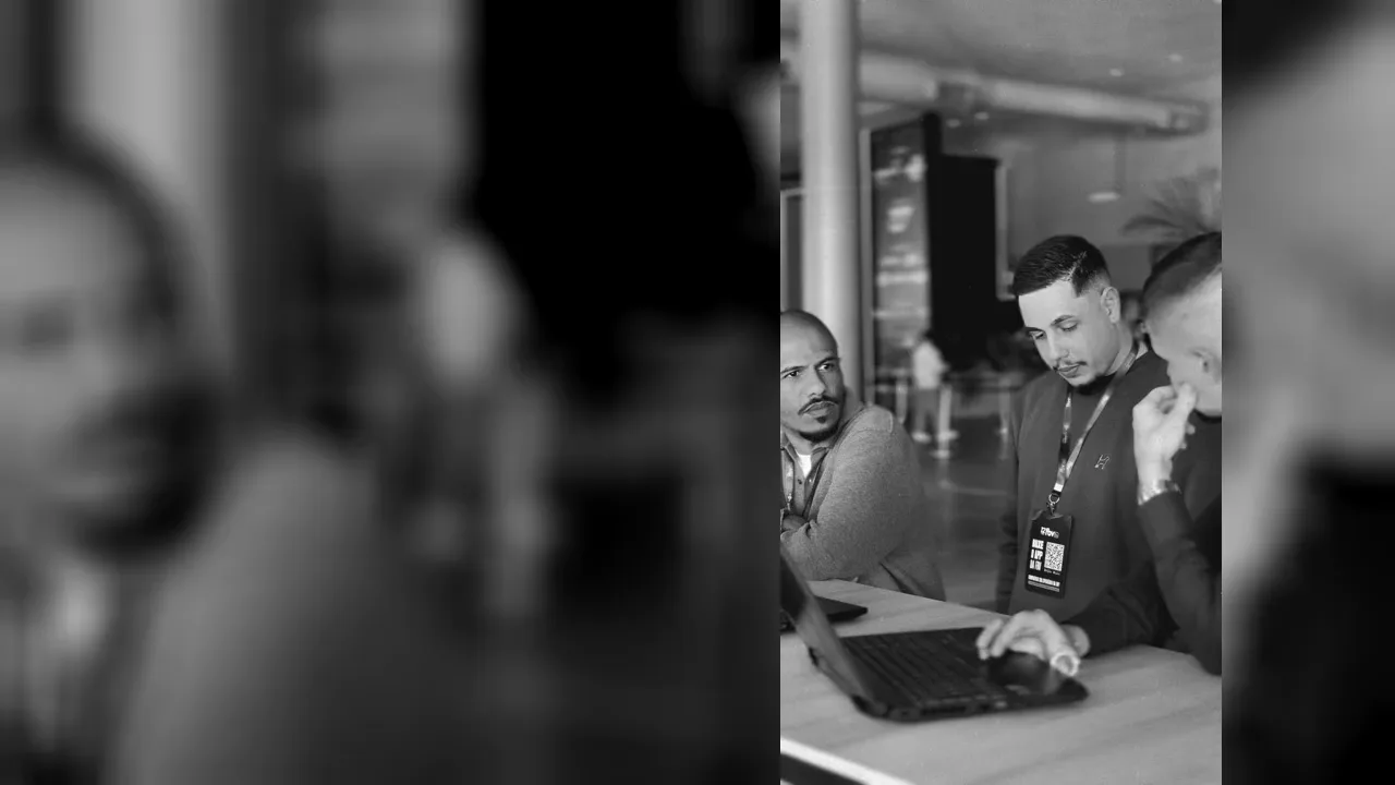 Registro em preto e branco de uma conversa da equipe Base Sul ao redor de um notebook